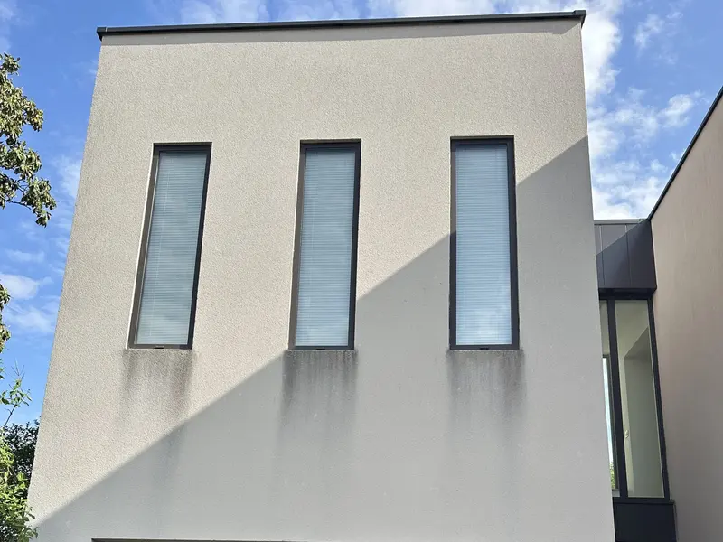 Avant : façade enduite avec des coulures noires sous les trois fenêtres
